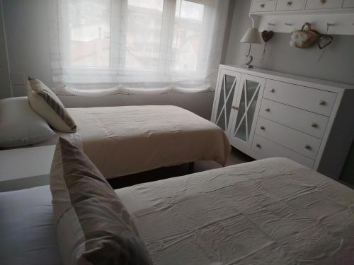 a bedroom with two beds and a dresser and a window at Areal de Esteiro in Esteiro-Muros