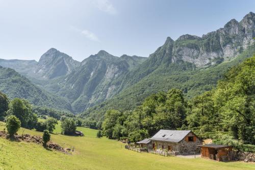 a barn in a field with mountains in the background at Gîte L'authentik in Accous