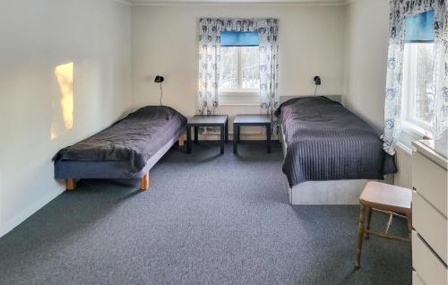 a bedroom with two beds and a table and windows at Amazing Home In Vetlanda With Wifi in Vetlanda
