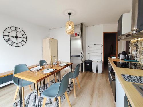 une cuisine avec une table et des chaises et une horloge au mur dans l'établissement Appartement 4 chambres - CAEN, à Caen