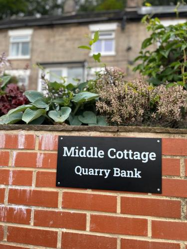 a sign on a brick wall with some plants at Middle Cottage Alton Towers, Peak District, JCB in Croxden