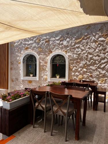 a dining room with wooden tables and chairs and a stone wall at ByAKKAN HOTEL in Bodrum City