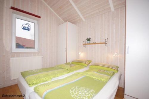 a bedroom with a bed with green and yellow sheets at 6 Personen Ferienhaus mit privatem Bootsteg, dikekter Seelage, Kanu, Whirlpool, Sauna und Kaminofen in Otterndorf in Otterndorf