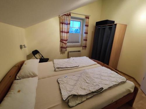 two beds in a small room with a window at 6 Personen Familienferienhaus mit Sauna, Whirlpool zwei Toiletten und Kaminofen in Otterndorf in Otterndorf