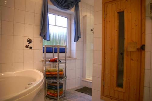 a bathroom with a tub and a sink and a window at 6 Personen Familienferienhaus mit Sauna, Whirlpool zwei Toiletten und Kaminofen in Otterndorf in Otterndorf