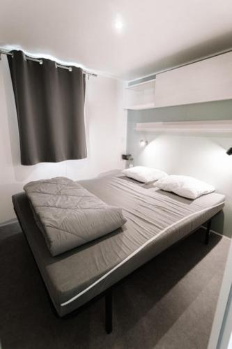 a bed with two pillows on it in a room at Camping Le Littoral in Le Grau-dʼAgde
