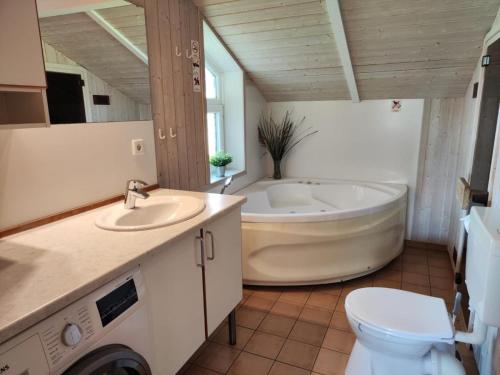 a bathroom with a tub and a sink and a toilet at 6 Personen Ferienhaus mit Sauna, Whirlpool, Kaminofen und Kanu in 2. Rheie zum See in Otterndorf in Otterndorf