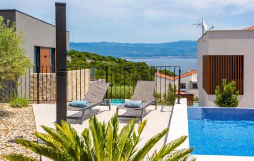 a patio with two chairs and a swimming pool at Holiday home Villa Vrbnik by Villas guide in Vrbnik
