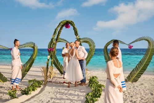 a wedding party on the beach with a heart shaped arch at ROBINSON MALDIVES - Adults only in Gaafu Alifu Atoll