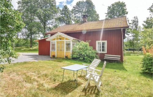 a red house with a table and a chair in front of it at Holiday Home Bön Granbacken Brålanda in Sörbo