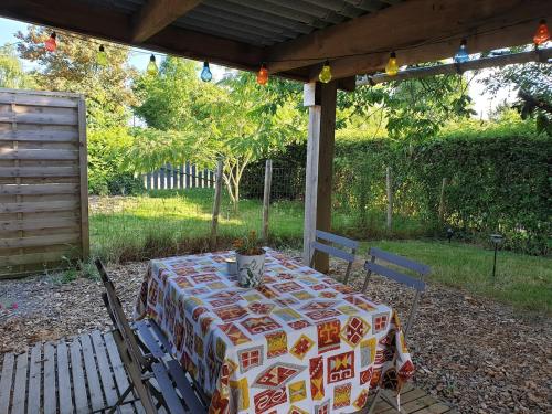 a table with a table cloth sitting under a pergola at Petite maison proche Marais Poitevin, Puy dufou in La Ronde