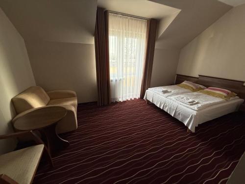 a bedroom with a bed and a chair and a window at Hotel Koziołek in Bodzentyn