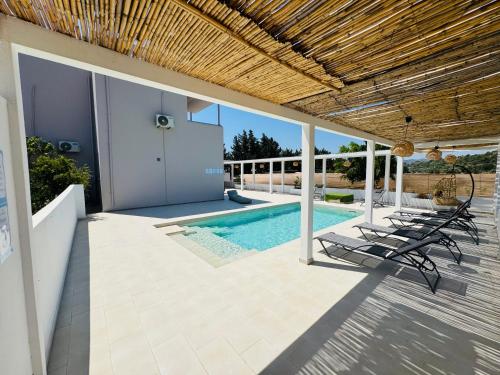 Un patio con sillas y una piscina. en Azure Dreams Villa with pool - Haraki beach, en Charaki