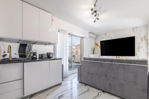 une cuisine avec des armoires blanches et une télévision à écran plat dans l'établissement LB Vacation Rentals I A Quiet Place with Terrace in the Heart of Cannes, à Cannes