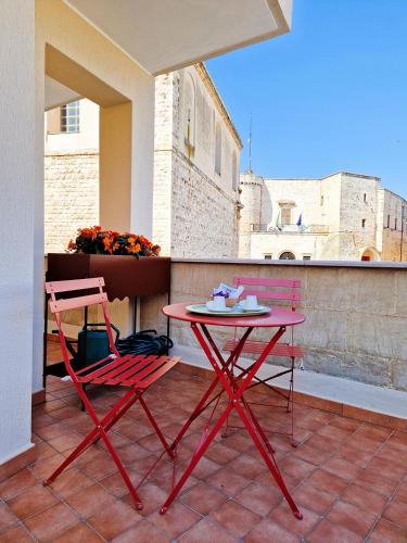 a red table and two chairs on a balcony at Dimora Odigitria in Bitritto