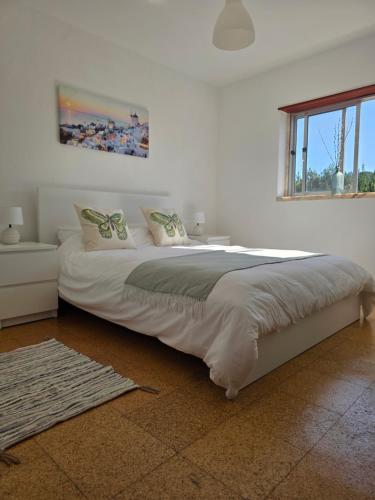 a bedroom with a large white bed with a window at Casas da Vila in Vila de Rei