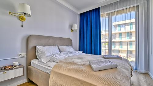 una camera da letto con un letto e una grande finestra di Rezydencja Niechorze D207 Classik z Basenem i SPA - 5D Apartments a Niechorze