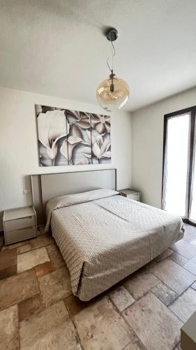 a bedroom with a bed and a painting on the wall at HomeStyle Agorà in Villasimius