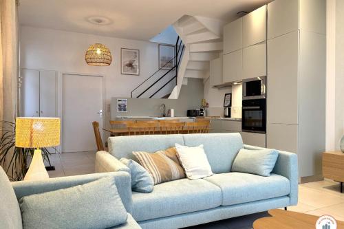 un salon avec un canapé bleu et une cuisine dans l'établissement Les Roches Noires - Terrasse Vue Mer, à Trouville-sur-Mer