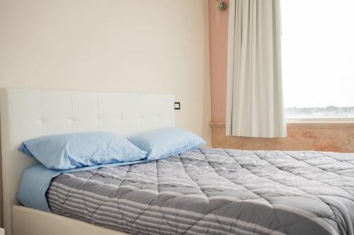 a bed with blue pillows in a room with a window at The Lodge Salento - San Foca in San Foca