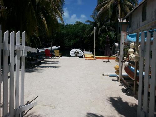 a beach with a white fence and chairs and trees at Sea n sun Guest House in Caye Caulker