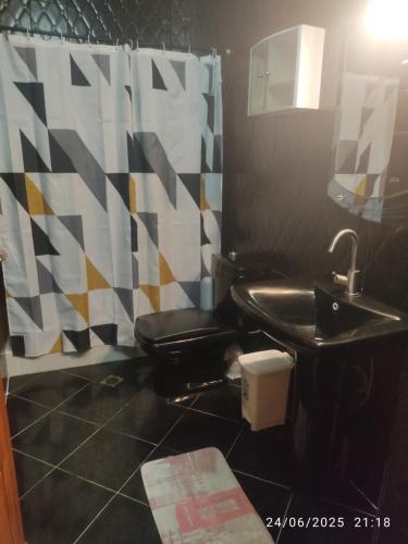 a bathroom with a black toilet and a sink at Mogadorista pour les familles in Essaouira