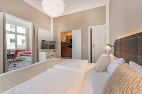 ein Schlafzimmer mit einem großen weißen Bett und einem Fernseher in der Unterkunft Villa Carmen Strandkorb in Ahlbeck