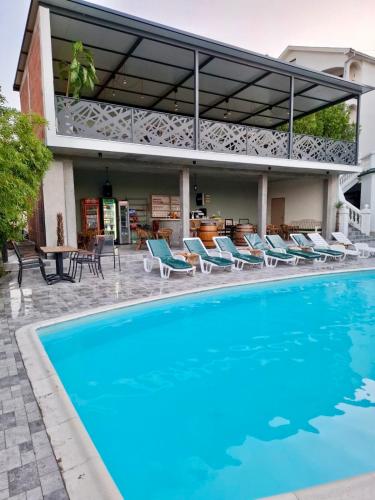 a swimming pool with chairs and a house at City view & pool apartment in Niš