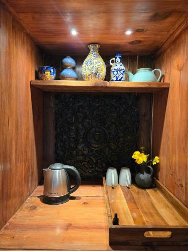 a wooden shelf with vases and a tea kettle on it at Himalyan Village Hideout -by Dhyanasadan in Almora