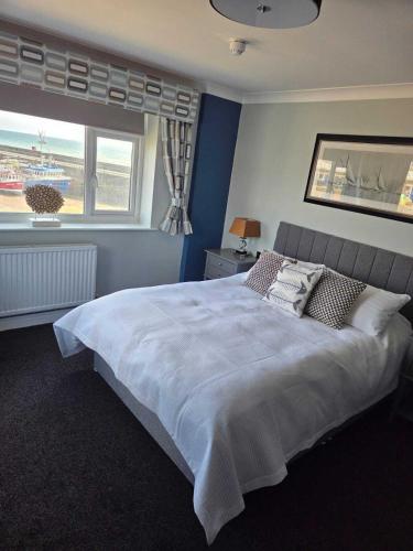 a bedroom with a large white bed with a window at Salt on the Harbour in Bridlington
