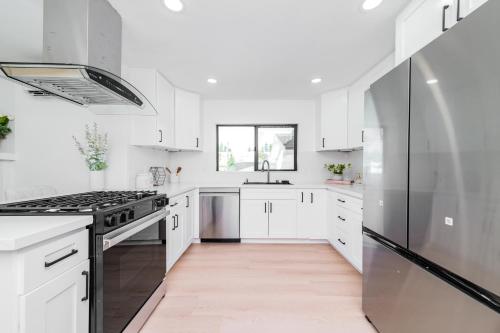 a kitchen with white cabinets and a stainless steel refrigerator at #Marbella Lane - Classy 3BR Jewel with Open Vibe in Yorba Linda