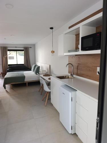 a kitchen with a sink and a bedroom with a bed at Pinomar - Emar Hotels in Es Calo
