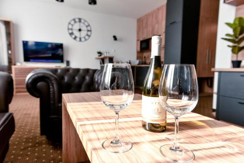 two wine glasses on a table with a bottle of wine at Hotel Milenium in Legnica