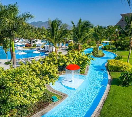 a resort pool with a red umbrella in the middle at Vidanta Villas Golf - Jacuzzi, Alberca, Lago in Acapulco