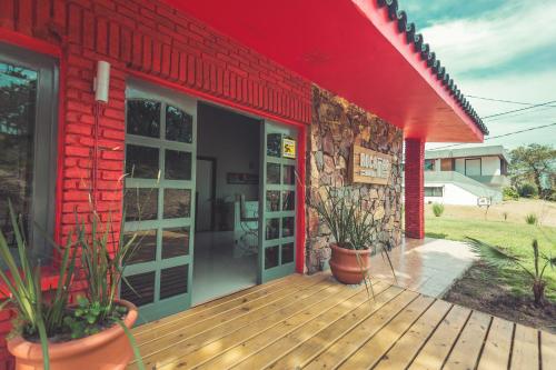 a red building with a wooden deck with potted plants at RocaMar Hostel Boutique in Punta del Este