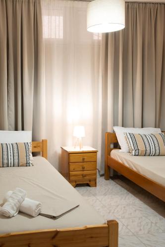 a bedroom with two beds and a table with a lamp at Ifigenia sea view in Artemida