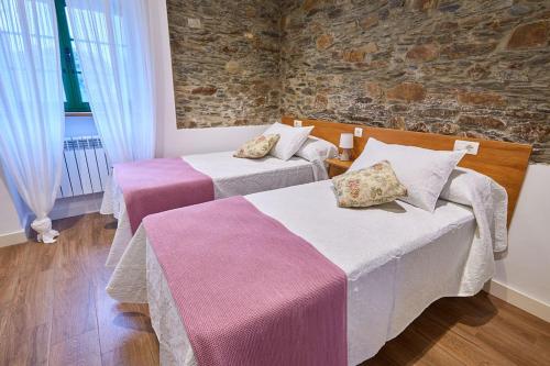 a room with two beds and a stone wall at Casa Choureiro Apartamentos Rurales in Navia