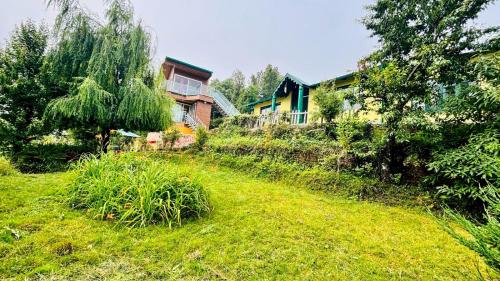 une cour herbeuse avec une maison en arrière-plan dans l'établissement Fairmont cottage Mukteshwar, à Mukteswar