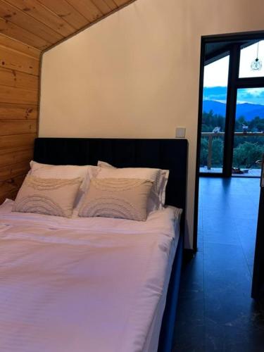 a bed with white sheets and pillows in a room at Forest Cuib in Predeluţ
