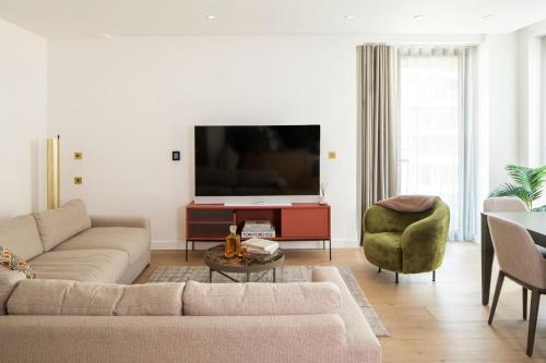 a living room with a couch and a tv at Kings Cross - Luxury 3 Bed Apartment, Private Balcony in London