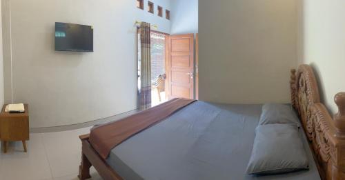 a bedroom with a bed and a television on the wall at Omah Perengkembang By Secoms in Ngingas