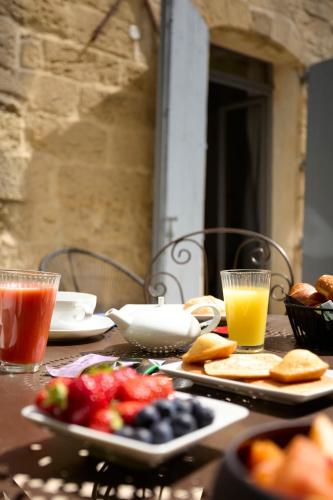a table topped with plates of food and glasses of juice at Boutique Hôtel Entraigues in Uzès