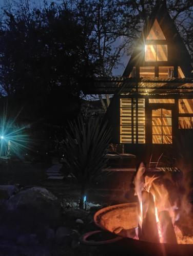 a fire pit in front of a house at night at Lodge Rincon Nativo in Hijuelas