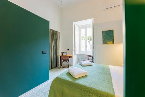 a bedroom with a green bed and a desk at Assoli House in Naples
