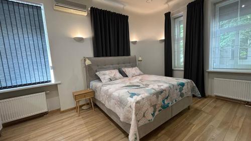 een slaapkamer met een bed en twee ramen bij LAIMA RENDEZVOUS APARTMENTS in Rīga