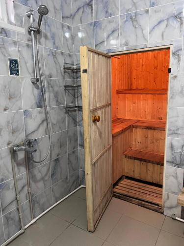 a bathroom with a shower and a wooden door at Guest house and yurt camp "Aktan" in Bokonbayevo