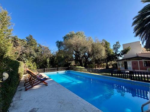 a swimming pool with a bench in front of a house at Posada del Valle solo adultos in Merlo