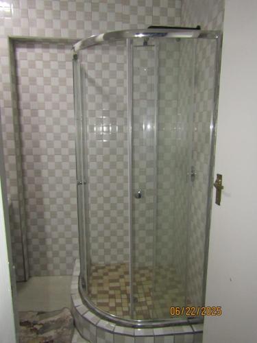 a shower with a glass door in a bathroom at The PHOMOLONG GUEST HOUSE in Roodepoort