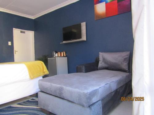 a bedroom with a bed and a couch and a tv at The PHOMOLONG GUEST HOUSE in Roodepoort