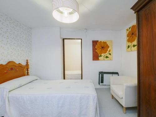 una camera da letto bianca con un letto e una sedia di Cubo's Casa Rural El descanso del Caminito del Rey ad Ardales